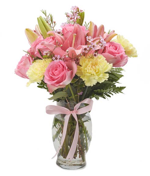 Yellow carnations, light pink roses and yellow carnations in a vase