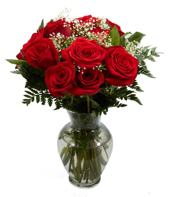 10 red roses with white babies breath and greens in a clear glass vase