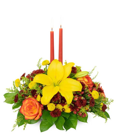 Yellow lily flower and candle centerpiece with two orange candles
