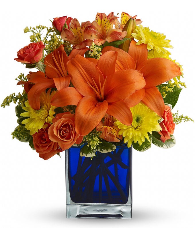 A Bouquet of Orange Asiatic Lilies, Orange Spray Roses, Orange Alstroemeria, Yellow Cushion Spray Mums, and Solidago in a Blue Cube Vase