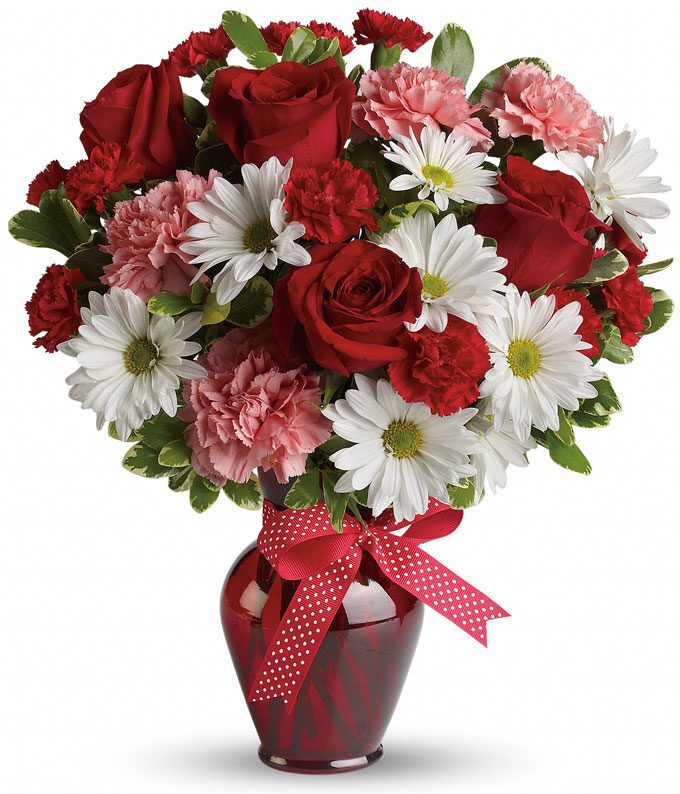 A bouquet of Red Roses, Pale Pink Carnations, Ruby Mini Carnations and White Daisy Spray Mums in a Dark-Red Glass Vase with a Decorative Bow
