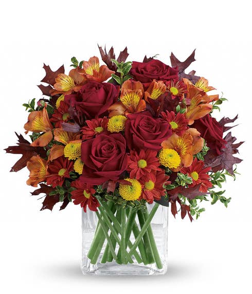Fall red roses and yellow poms mixed fall flowers bouquet in a clear cube vase