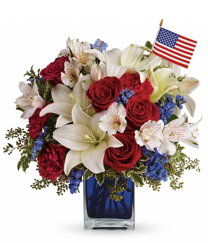 A Bouquet of Red Roses, White Asiatic Lilies, Scarlet Carnations, Blue Statice, and White Alstroemeria in a Blue Cube Vase
