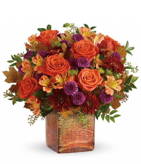 Orange roses, orange alstroemeria and purple mums in a square orange vase