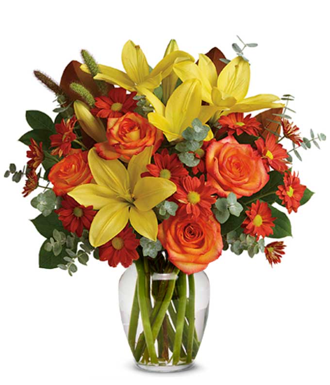 A Bouquet of Yellow Asiatic Lilies, Red Daisy Spray Chrysanthemums, Orange Roses, Millet, Magnolia Leaves, Spiral Eucalyptus, and Lemon Leaf in a Clear Glass Vase with Card Message