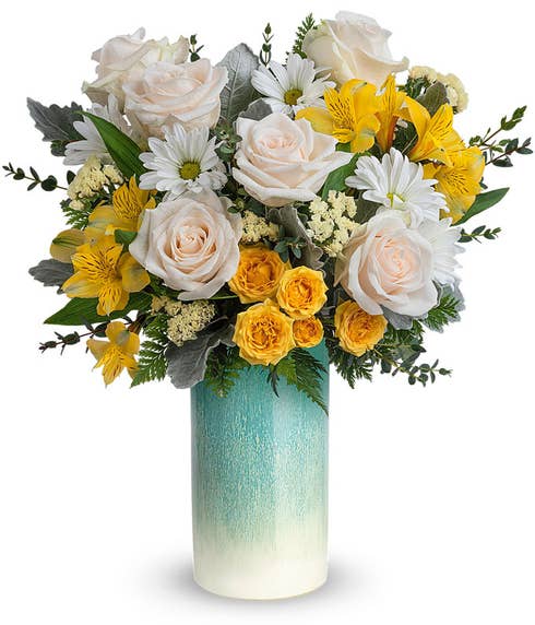 Tall arrangement of white roses and yellow flowers, in a tall turquois ombre cylinder vase