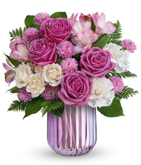 Short arrangement of purple and white flowers, in a purple cylinder vase