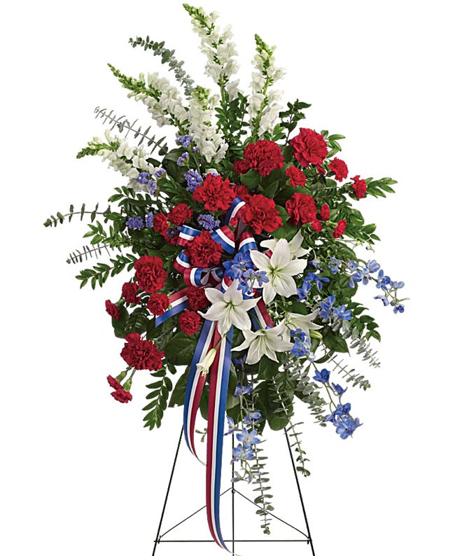 Standing Spray Including Red Carnations, White Asiatic Lilies, White Snapdragons, Blue Delphinium, and Assorted Lush Greens with Patriotic Ribbon