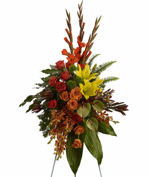 Orange orchid, orange rose, and red gladioli oval funeral flowers standing spray