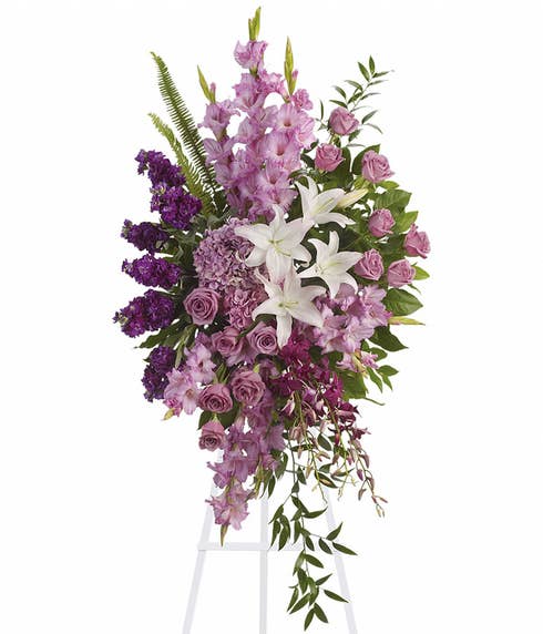 Oval shaped lavender roses and gladioli funeral flowers standing spray