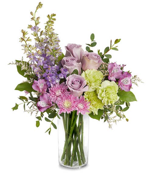 A Mother's Day arrangement featuring lavender roses, purple alstroemeria, green carnations, lavender larkspur, cushion chrysanthemums, and floral greenery, arranged in a keepsake lavender butterfly pitcher, with space for a personalized gif