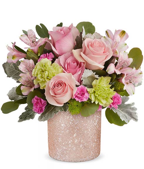 A Mother's Day arrangement featuring pink roses, light pink alstroemeria, green carnations, cushion spray chrysanthemums, and floral greens, arranged in a keepsake blush shimmering vase, with space for a personalized gift message.