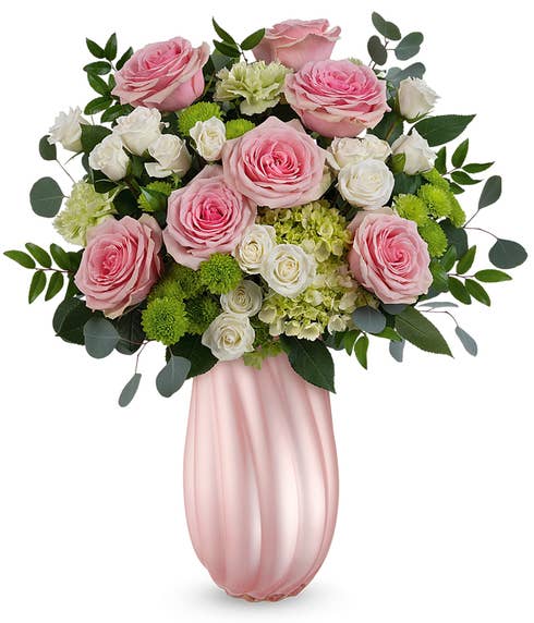 A Mother's Day arrangement featuring green hydrangea, pink roses, white spray roses, green carnations, green button chrysanthemums, and floral greenery, arranged in a keepsake pearl pink swirling vase, with space for a personalized gift mes