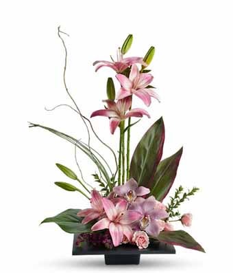 A Bouquet of Pink Lilies, Pink Roses, Pink Cymbidium Orchids, Variegated Ti Leaves, Bear Grass and Curly Willow in a Black Glass Vase