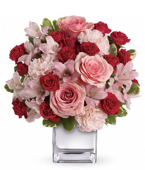 Pink roses, red spray roses and pink alstroemeria in a square vase