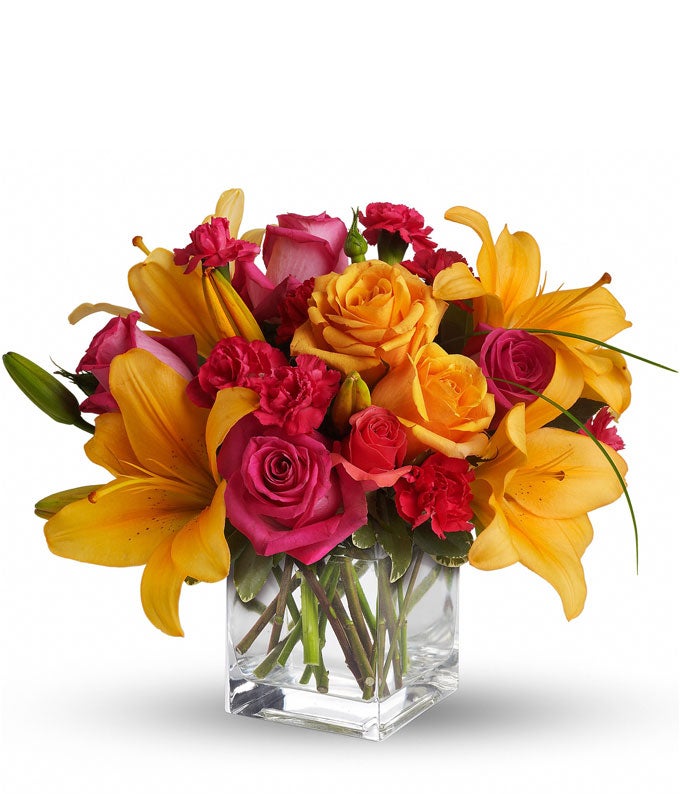 A Bouquet of Hot Pink Roses, Orange Roses, Hot Pink Spray Roses, Orange Asiatic Lilies, Hot Pink Carnations (Regular & Deluxe Only), Hot Pink Mini Carnations (Regular & Deluxe Only), Variegated Pittosporum and Bear Grass in a Clear Cube Vase with Personalized Card Message