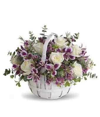 A Bouquet of White Roses, Lavender Waxflower, Purple Alstroemeria, and Spiral Eucalyptus in a White Wicker Basket