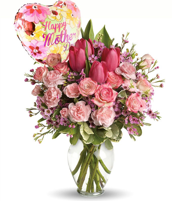 A bouquet including Blush Roses, Hot-Pink Tulips, Light-Pink Carnations, Pitta Negra, Variegated Pittosporum, and Wax Flower with Mother Themed Mylar Balloon in a Glass Vase