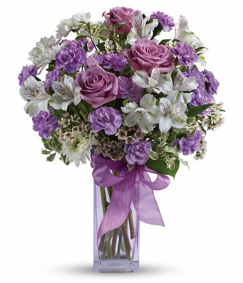 Lavender rose and lavender carnations bouquet inside a purple glass vase