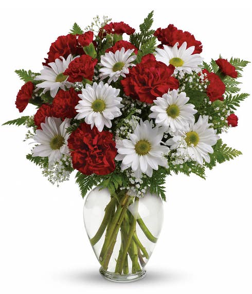 White daisy and re carnations flower bouquet in a clear glass vase with card