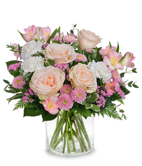 Blush roses, pin alstroemeria, white carnations, pink button chrysanthemums , raspberry sinuata statice, and floral greens in a pink & white frost glass vase