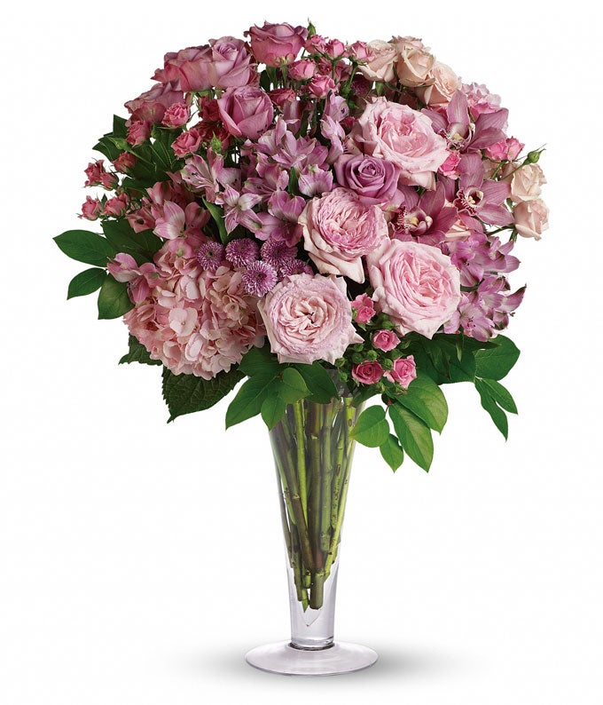 A Bouquet of  Pink Hydrangea, Pink Orchids, Pink Roses, Lavender Roses, Pink Spray Roses, Pink Alstroemeria, Lilac Hued Button Mums, and Lush Greens in a Glass Vase