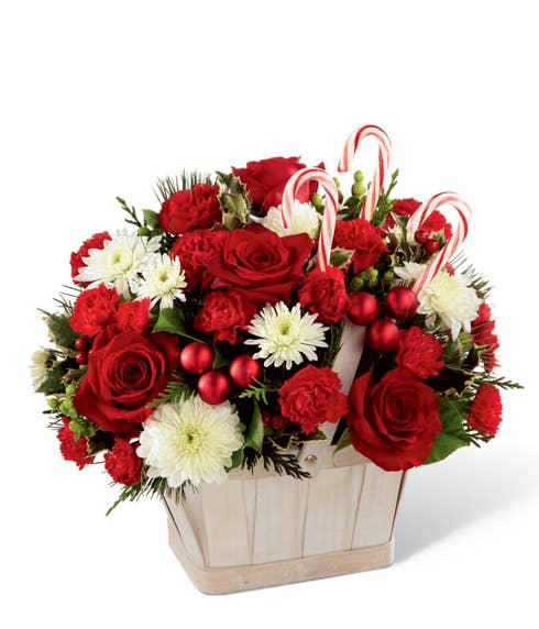 Red roses, red carnations and candy canes in a woven basket