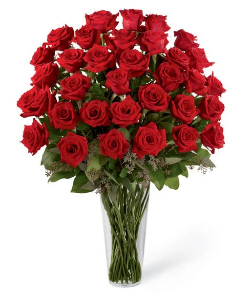 Dozen long stem red roses in classic glass vase with seeded eucalyptus